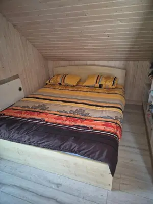 a bed in a room with a wooden ceiling at Sodyba Pirtis Panarvė in Lazdijai