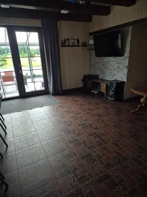 a room with a brick floor and a flat screen tv at Sodyba Pirtis Panarvė in Lazdijai