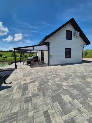 a building with a roof with a patio at Sodyba Pirtis Panarvė in Lazdijai