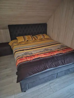 a large bed in a room with a wooden floor at Sodyba Pirtis Panarvė in Lazdijai