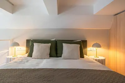 a bedroom with a bed with green and white pillows at Brand New Loft Naujamiestis in Vilnius
