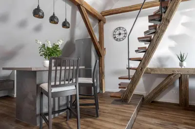 a dining room with a table and chairs and a staircase at ALL SAINTS Residence in Vilnius