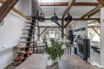 a spiral staircase in a living room with a table and flowers at ALL SAINTS Residence in Vilnius