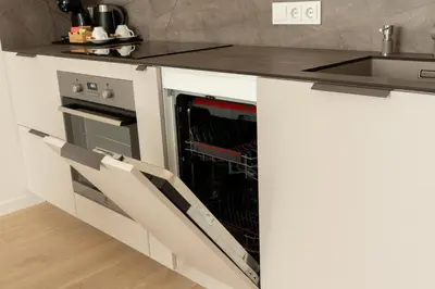a kitchen with an open dishwasher in a white kitchen at Cozy home night and day in Kaunas