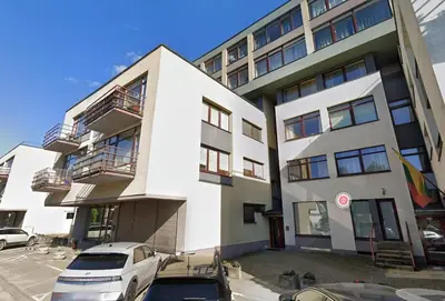 a white building with cars parked in front of it at Panorama Apartment Balcony Work Castle View in Vilnius