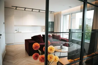 a living room with a couch and a table with flowers at City Breeze Flat, Self Ceck-In, Free parking in Vilnius