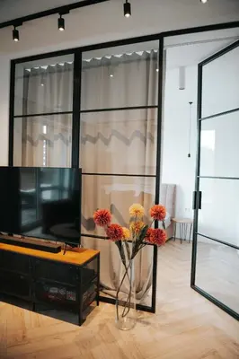a living room with a television and flowers in a vase at City Breeze Flat, Self Ceck-In, Free parking in Vilnius