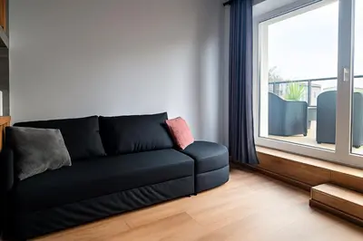 a black couch in a living room with a window at Zveryno City Appartments in Vilnius