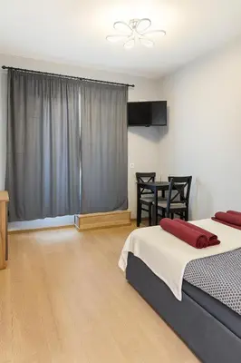 a bedroom with two beds and a dining room at Zveryno City Appartments in Vilnius