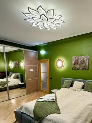 a green bedroom with two beds and a chandelier at Downtown Kaunas - Maironis 10 in Kaunas