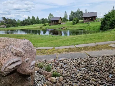 a rock garden in front of a pond with houses at VIP forest dreams villa 2 in Leliūnai