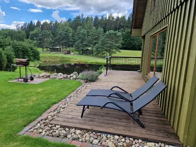 a blue bench sitting on a deck next to a house at VIP forest dreams villa 2 in Leliūnai