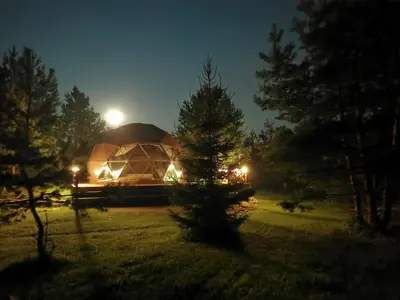 a large tent with lights in a field at night at Skubėk Neskubėti in Klykiai