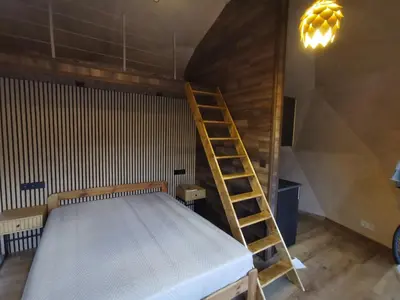 a bed with a wooden ladder in a room at Skubėk Neskubėti in Klykiai