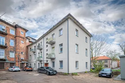 a white building with cars parked in a parking lot at The Comfort Apartment #1 by Polo Apartments in Kaunas
