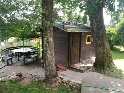 a small cabin with a table and two trees at Kaimo turizmo sodyba