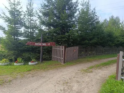 a wooden fence with a street sign next to a dirt road at Kaimo turizmo sodyba