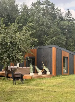 a black house with a couch in a field at Forest Resort house