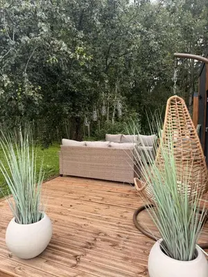 two white vases sitting on a wooden deck with a couch at Forest Resort house