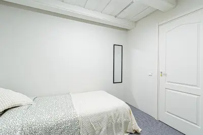 a white bedroom with a bed and a door at STAY Kaunas city center in Kaunas