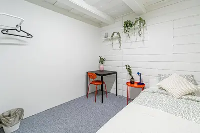 a white bedroom with a bed and a table at STAY Kaunas city center in Kaunas