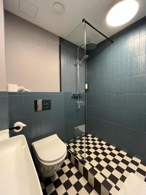 a bathroom with a toilet and a black and white checkered floor at Modern Room in Central Vilnius in Vilnius