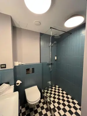 a bathroom with a toilet and a shower with blue tiles at Modern Room in Central Vilnius in Vilnius