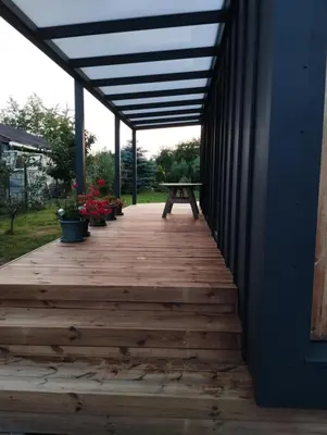 a wooden porch with a picnic table and potted plants at Namelis soduose in Akademija