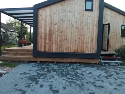 a house with a wooden wall and a patio at Namelis soduose in Akademija