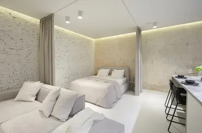 a bedroom with two beds and a couch and a brick wall at Provokatas in Kaunas