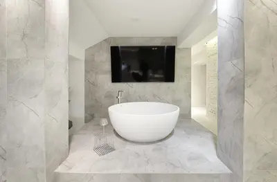 a bathroom with a tub and a tv on a wall at Provokatas in Kaunas