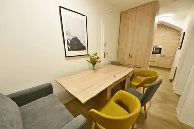 a living room with a wooden table and yellow chairs at Domillion 2bdr 2bath on Vokieciu w parking V1020A in Vilnius