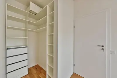 a walk in closet with white shelves and a door at Domillion Penthouse 2bdr 2bath P364a in Vilnius