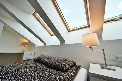 a bedroom with a bed with a lamp and windows at Domillion Penthouse 2bdr 2bath P364a in Vilnius