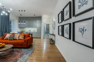 a living room with an orange couch and a kitchen at Domillion new modern 2bdr City Hall apt D1117B in Vilnius