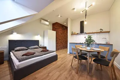 a bedroom with a bed and a table and a kitchen at Domillion New modern Vilnius old town studio U2302 in Vilnius