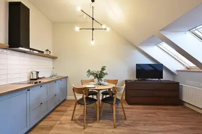 a kitchen with a table with chairs and a tv at Domillion New modern Vilnius old town studio U2302 in Vilnius
