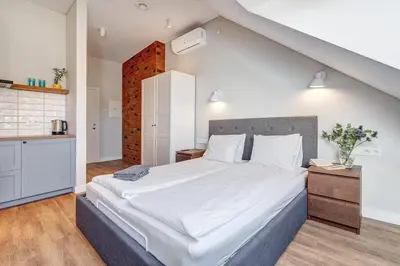 a bedroom with a large bed and a kitchen at Domillion New modern Vilnius old town studio U2304 in Vilnius