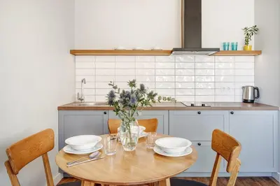 a kitchen with a wooden table with plates and bowls at Domillion New modern Vilnius old town studio U2304 in Vilnius