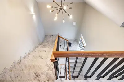 a staircase in a house with a chandelier at Domillion New modern Vilnius old town studio U2304 in Vilnius