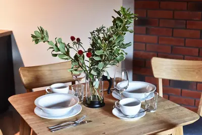 a wooden table with plates and a vase of flowers at Domillion 1bdr New old town apt U2305 in Vilnius