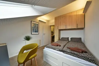 a bedroom with a bed and a yellow chair at Domillion Duplex Apt 11 ppl 4baths Vokieciu V10C in Vilnius
