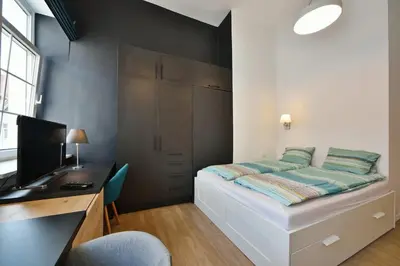 a bedroom with a bed and a desk with a computer at Domillion Duplex Apt 11 ppl 4baths Vokieciu V10C in Vilnius