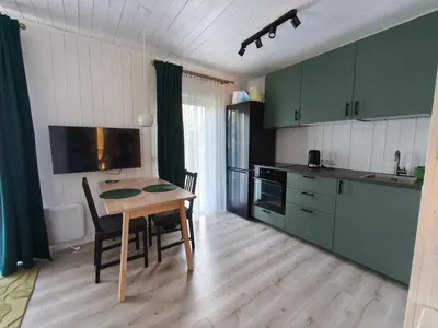 a kitchen with green cabinets and a table with chairs at Gervių takas 2
