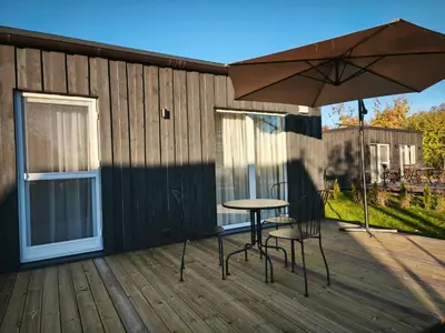 a table and chairs on a deck with an umbrella at Gervių takas 2