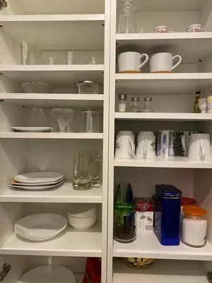 a white pantry with plates and cups and dishes at Paupio krantas in Vilnius