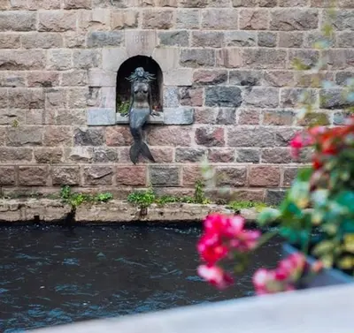 a statue of a bird on the side of a brick wall at Paupio krantas in Vilnius