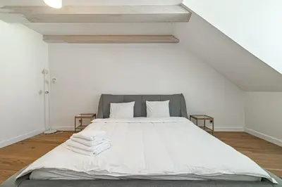 a white bedroom with a bed with white sheets and pillows at Spacious 3 BDR apartment in Old Town in Vilnius