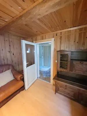 a room with a couch and a tv and a door at Šeimos namelis nr2-Mindūnų sodyba in Pakopi