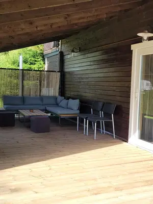 a patio with a blue couch and two chairs at Šeimos namelis nr2-Mindūnų sodyba in Pakopi